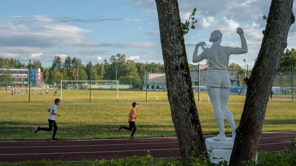 a statue of a man running next to a tree